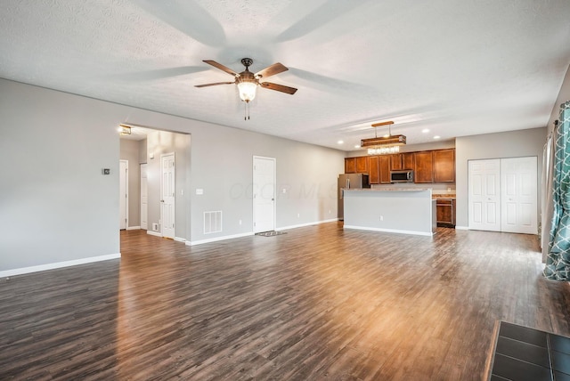 unfurnished living room featuring ceiling fan, dark hardwood / wood-style flooring, and a textured ceiling