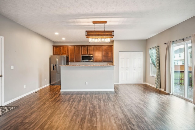 kitchen with dark hardwood / wood-style flooring, pendant lighting, stainless steel appliances, and a textured ceiling