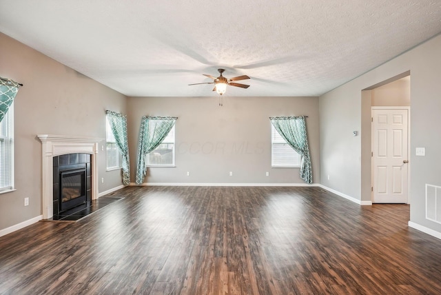 unfurnished living room featuring a textured ceiling, ceiling fan, dark wood-type flooring, and a tile fireplace