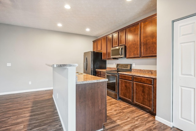 kitchen featuring a textured ceiling, stainless steel appliances, and dark hardwood / wood-style floors