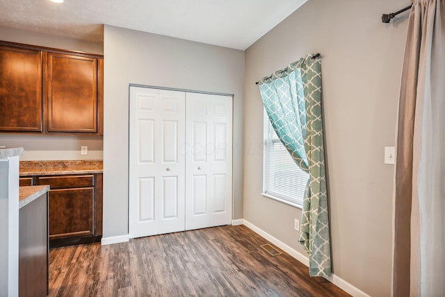 kitchen with light stone countertops, built in desk, and dark hardwood / wood-style floors