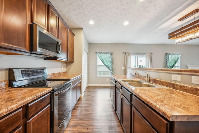 kitchen with a kitchen island with sink, dark wood-type flooring, sink, a textured ceiling, and stainless steel appliances