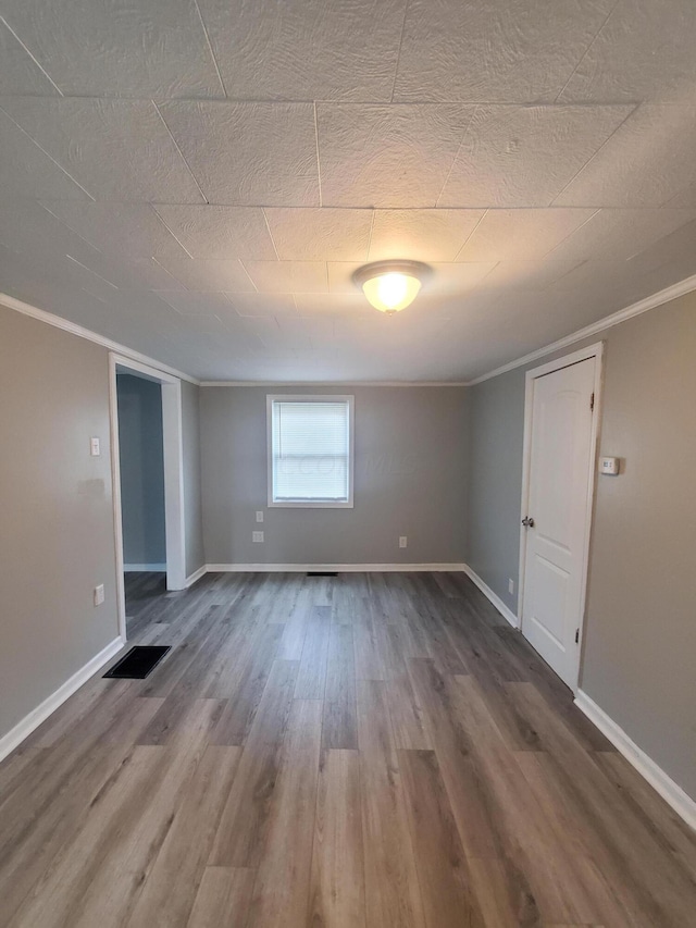 spare room with wood-type flooring and crown molding