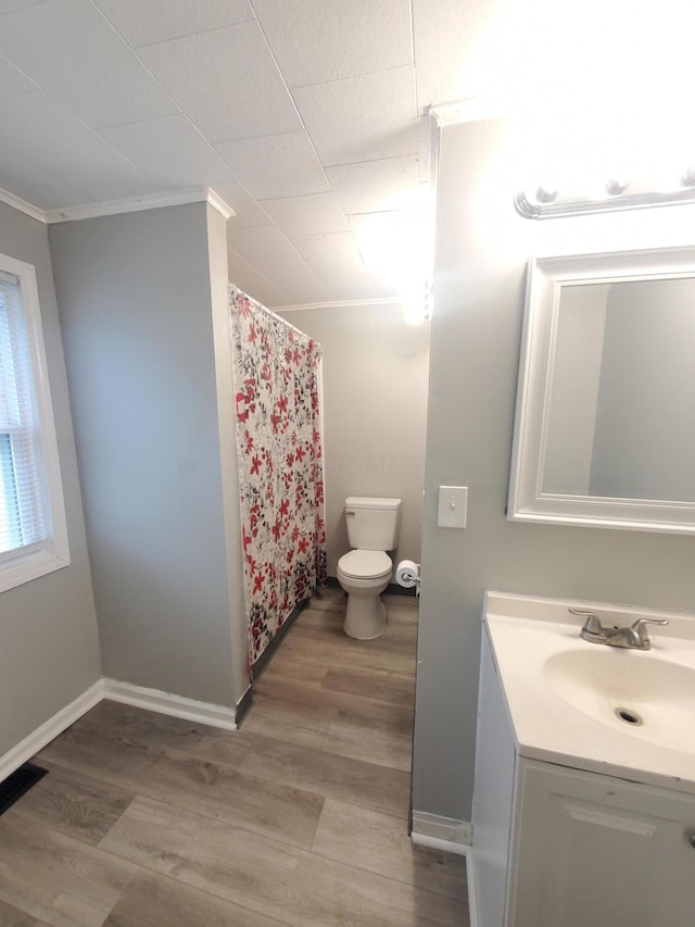 bathroom featuring hardwood / wood-style floors, vanity, ornamental molding, and toilet