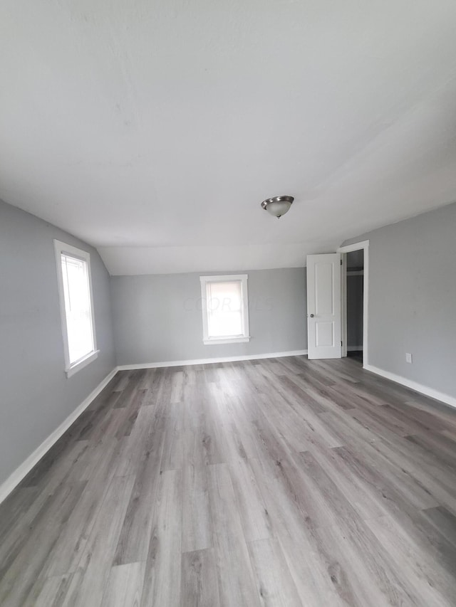 unfurnished room with plenty of natural light, vaulted ceiling, and light hardwood / wood-style flooring