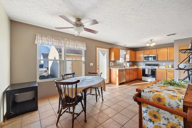 kitchen featuring sink, ceiling fan, light tile patterned floors, a textured ceiling, and stainless steel appliances