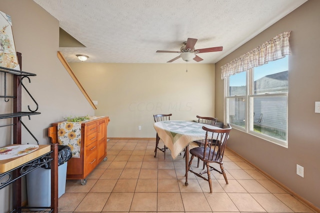 tiled dining room with ceiling fan and a textured ceiling