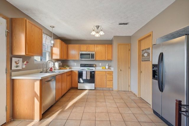 kitchen featuring appliances with stainless steel finishes, an inviting chandelier, pendant lighting, and sink