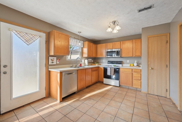 kitchen featuring an inviting chandelier, sink, light tile patterned floors, decorative light fixtures, and stainless steel appliances