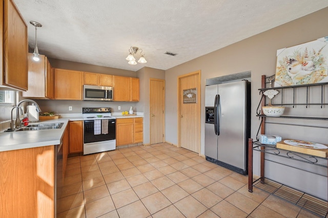 kitchen featuring a textured ceiling, stainless steel appliances, sink, an inviting chandelier, and hanging light fixtures