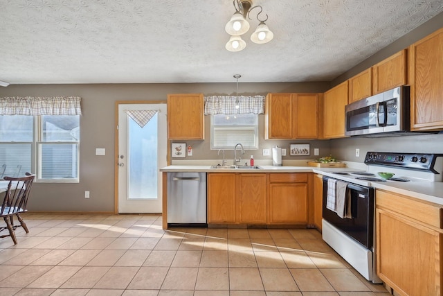 kitchen with sink, stainless steel appliances, pendant lighting, a textured ceiling, and light tile patterned floors