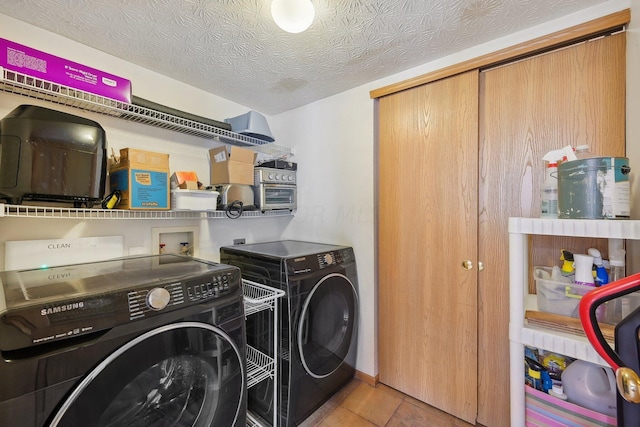 laundry room with light tile patterned flooring, a textured ceiling, and washing machine and clothes dryer