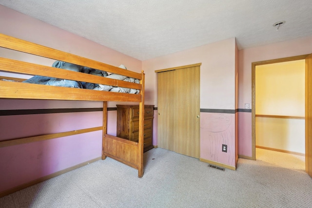 unfurnished bedroom featuring a textured ceiling, light colored carpet, and a closet