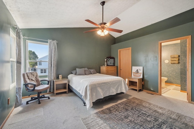 carpeted bedroom with a textured ceiling, ensuite bath, vaulted ceiling, and ceiling fan