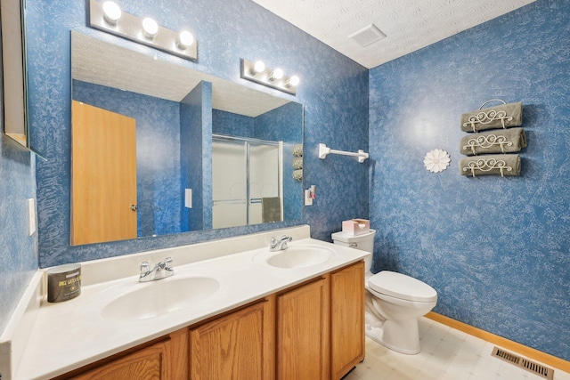 bathroom featuring vanity, a shower with shower door, a textured ceiling, and toilet