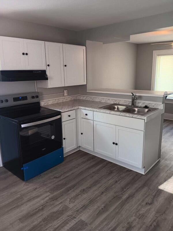 kitchen with dark hardwood / wood-style flooring, electric range, white cabinetry, and sink