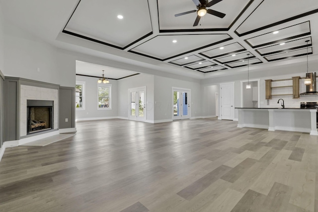 13917 Fantasy Way, Pickerington, OH 43147 - unfurnished living room featuring ceiling fan with notable chandelier, light hardwood / wood-style floors, coffered ceiling, and sink