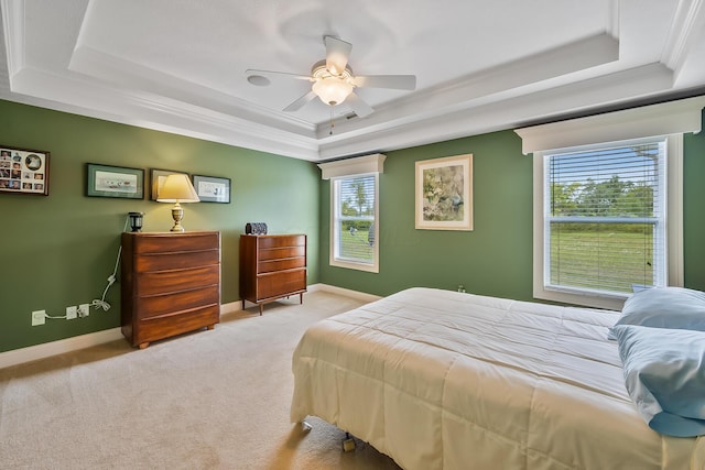 bedroom with ceiling fan, crown molding, light carpet, and a tray ceiling