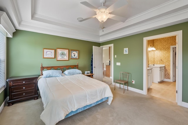 bedroom with ceiling fan, ensuite bathroom, light colored carpet, a tray ceiling, and ornamental molding