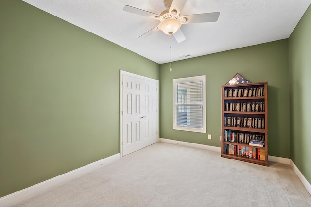 interior space featuring light carpet, a textured ceiling, and ceiling fan