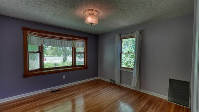 empty room with a textured ceiling and light wood-type flooring