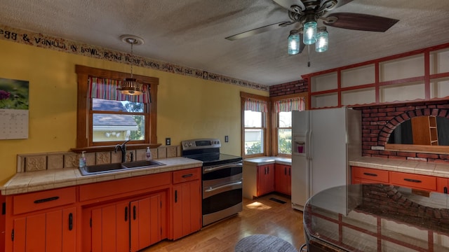 kitchen featuring tile countertops, stainless steel electric range, sink, light hardwood / wood-style flooring, and white fridge with ice dispenser