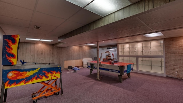 playroom with carpet flooring, wood walls, and a drop ceiling