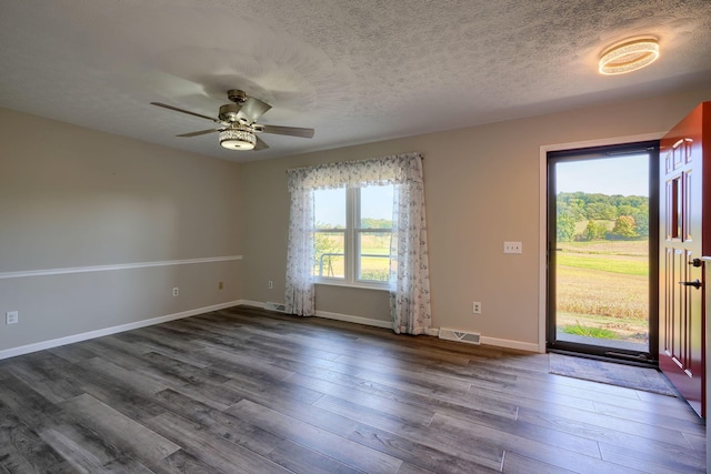 spare room with dark hardwood / wood-style floors, ceiling fan, a textured ceiling, and a wealth of natural light