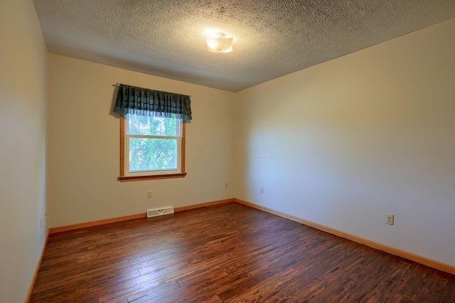 spare room featuring a textured ceiling and dark wood-type flooring