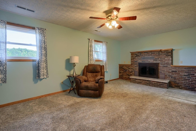 living area with carpet flooring, ceiling fan, a fireplace, and a textured ceiling