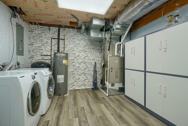 laundry area with electric water heater, heating unit, electric panel, washer and dryer, and light wood-type flooring