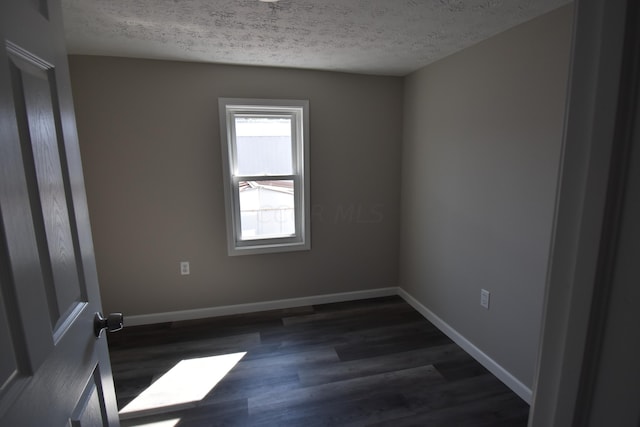 empty room featuring dark hardwood / wood-style floors and a textured ceiling