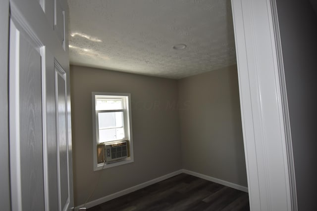 spare room with dark hardwood / wood-style flooring, cooling unit, and a textured ceiling