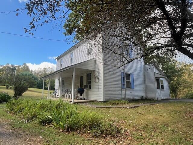 view of side of property featuring a porch and a lawn