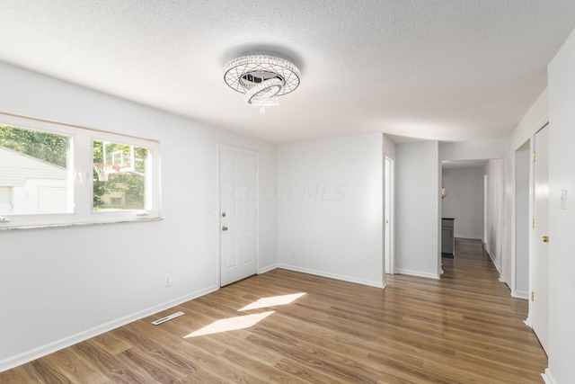 spare room with a textured ceiling and hardwood / wood-style flooring