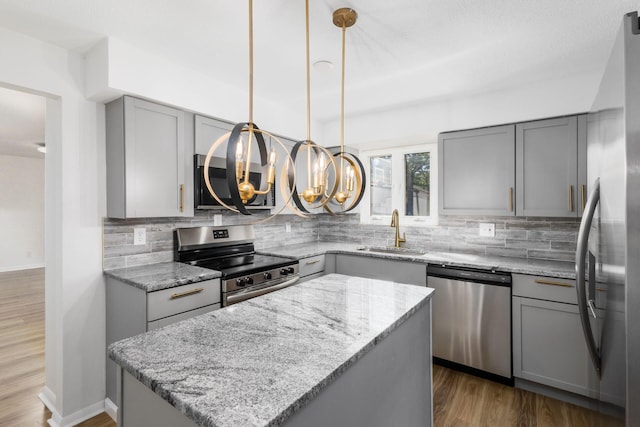 kitchen featuring appliances with stainless steel finishes, a center island, gray cabinetry, and sink