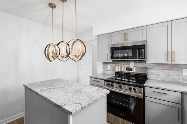 kitchen featuring decorative backsplash, appliances with stainless steel finishes, light stone counters, decorative light fixtures, and a kitchen island