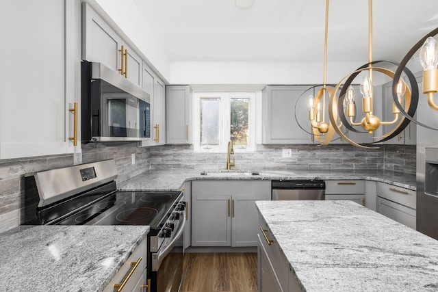 kitchen featuring appliances with stainless steel finishes, sink, pendant lighting, a notable chandelier, and gray cabinets