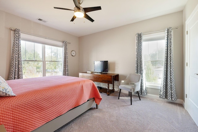 carpeted bedroom featuring multiple windows and ceiling fan