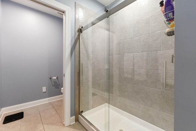 bathroom with tile patterned flooring, toilet, and a shower with door