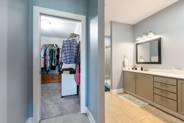 bathroom with tile patterned flooring, vanity, and walk in shower