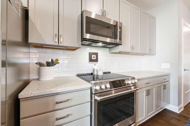 kitchen featuring backsplash, light stone counters, dark hardwood / wood-style flooring, and stainless steel appliances