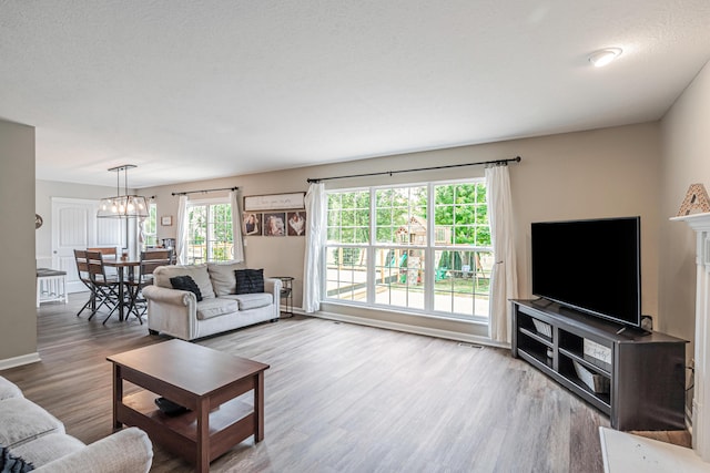 living room featuring hardwood / wood-style floors, a healthy amount of sunlight, a textured ceiling, and an inviting chandelier