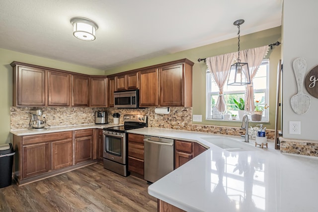 kitchen with sink, hanging light fixtures, stainless steel appliances, tasteful backsplash, and dark hardwood / wood-style floors