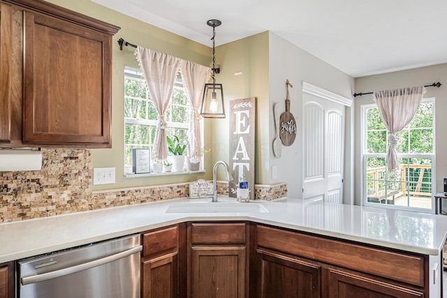 kitchen featuring stainless steel dishwasher, decorative backsplash, sink, and hanging light fixtures