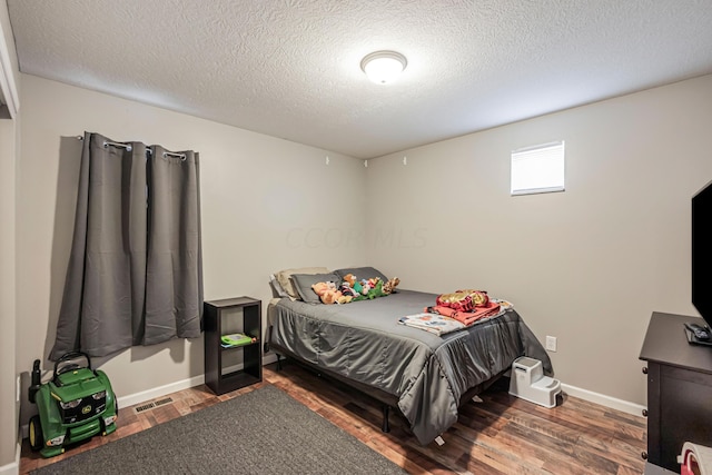 bedroom featuring a textured ceiling and dark hardwood / wood-style floors