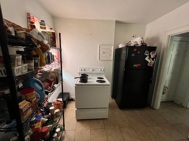 kitchen with electric range, black fridge, and light tile patterned floors