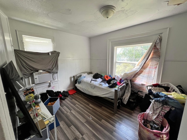 bedroom with wood walls, cooling unit, dark wood-type flooring, and a textured ceiling