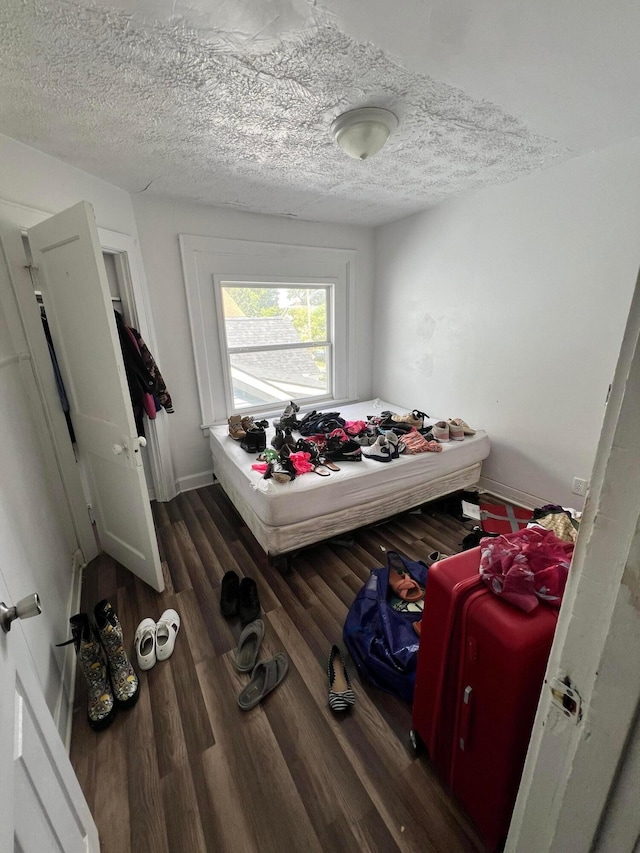 bedroom with a textured ceiling and dark hardwood / wood-style floors