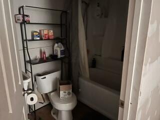 bathroom featuring toilet and shower / tub combo with curtain